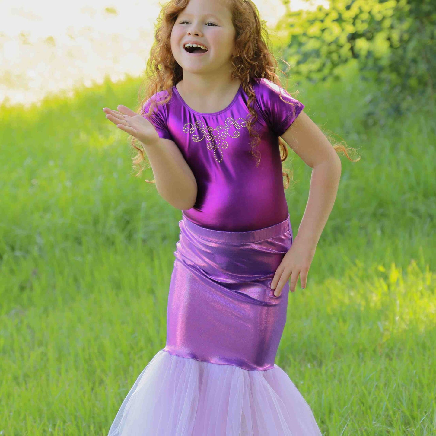 a little girl in a purple dress standing in the grass