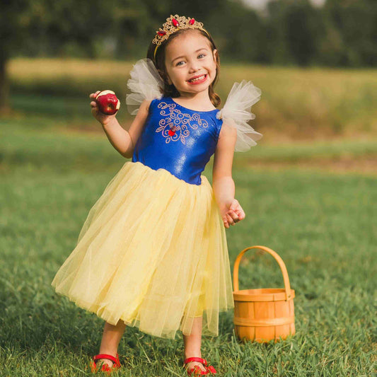 a little girl in a princess costume holding an apple