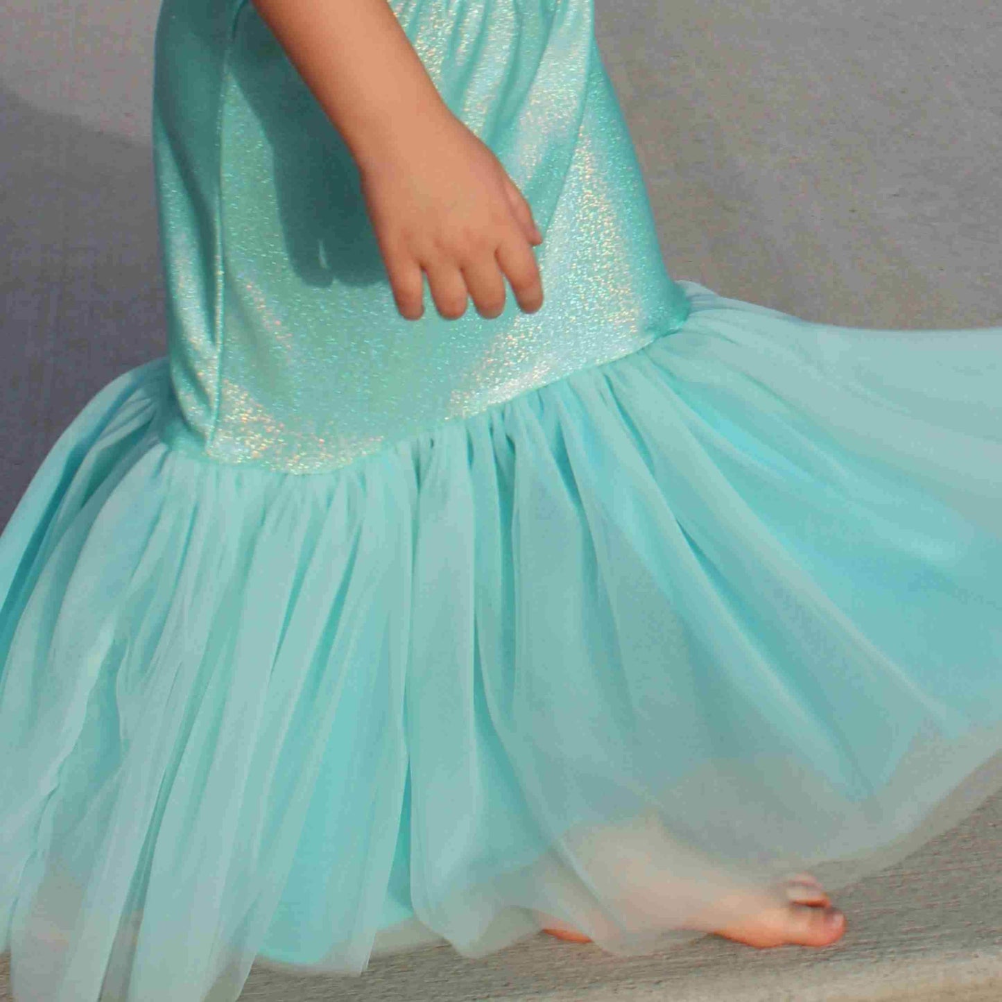 a little girl in a blue dress with her hand on her hip