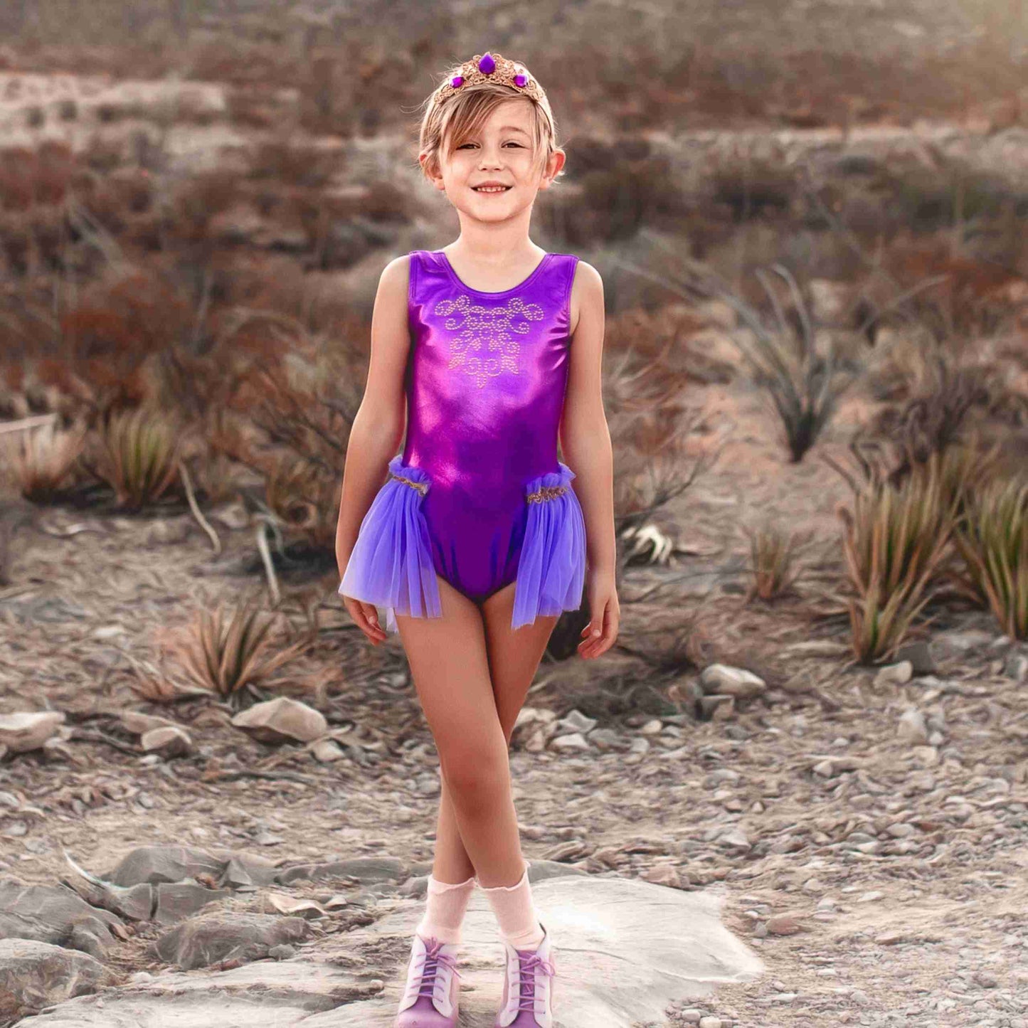 a little girl wearing a purple leotard and purple shoes