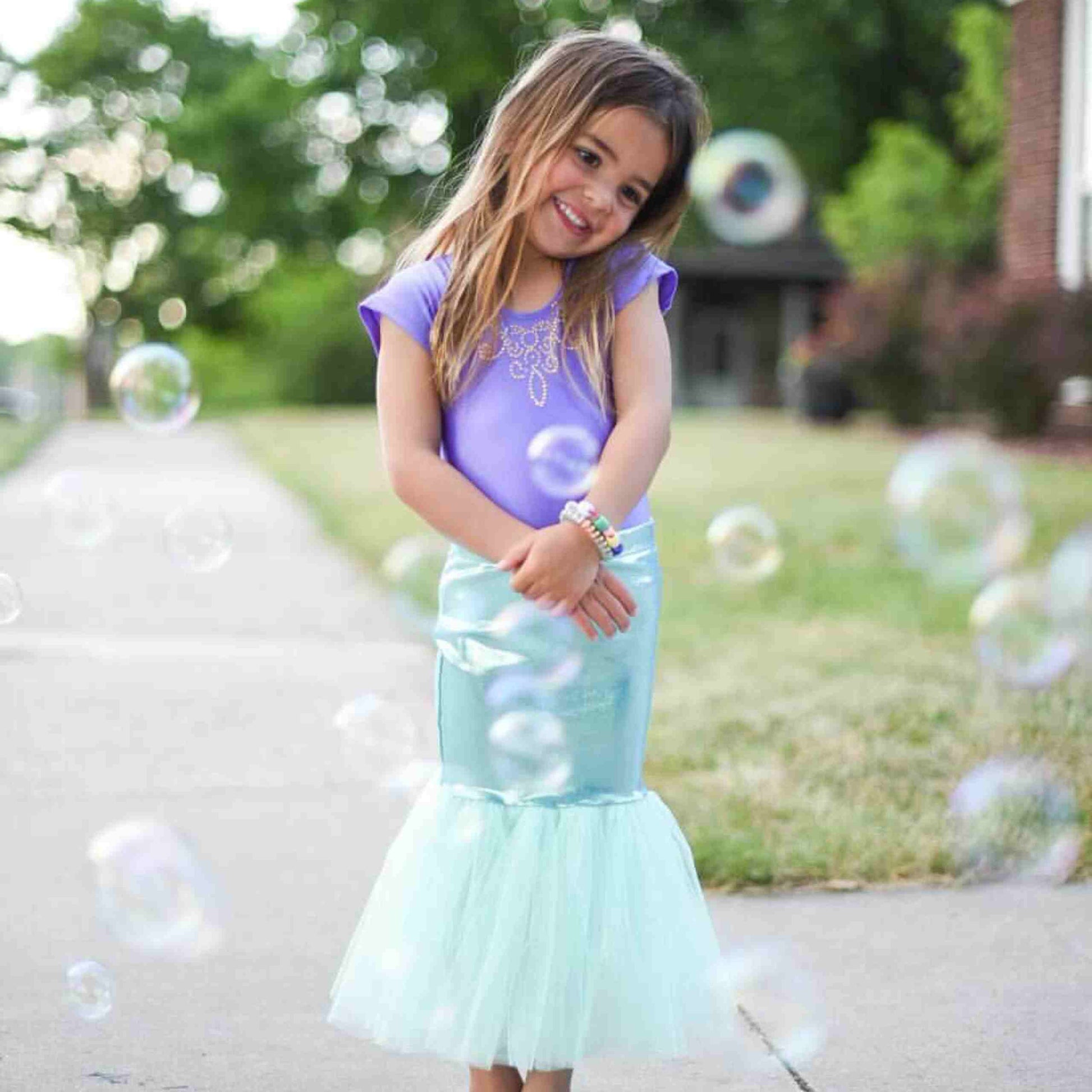 a little girl standing on a sidewalk with bubbles in the air
