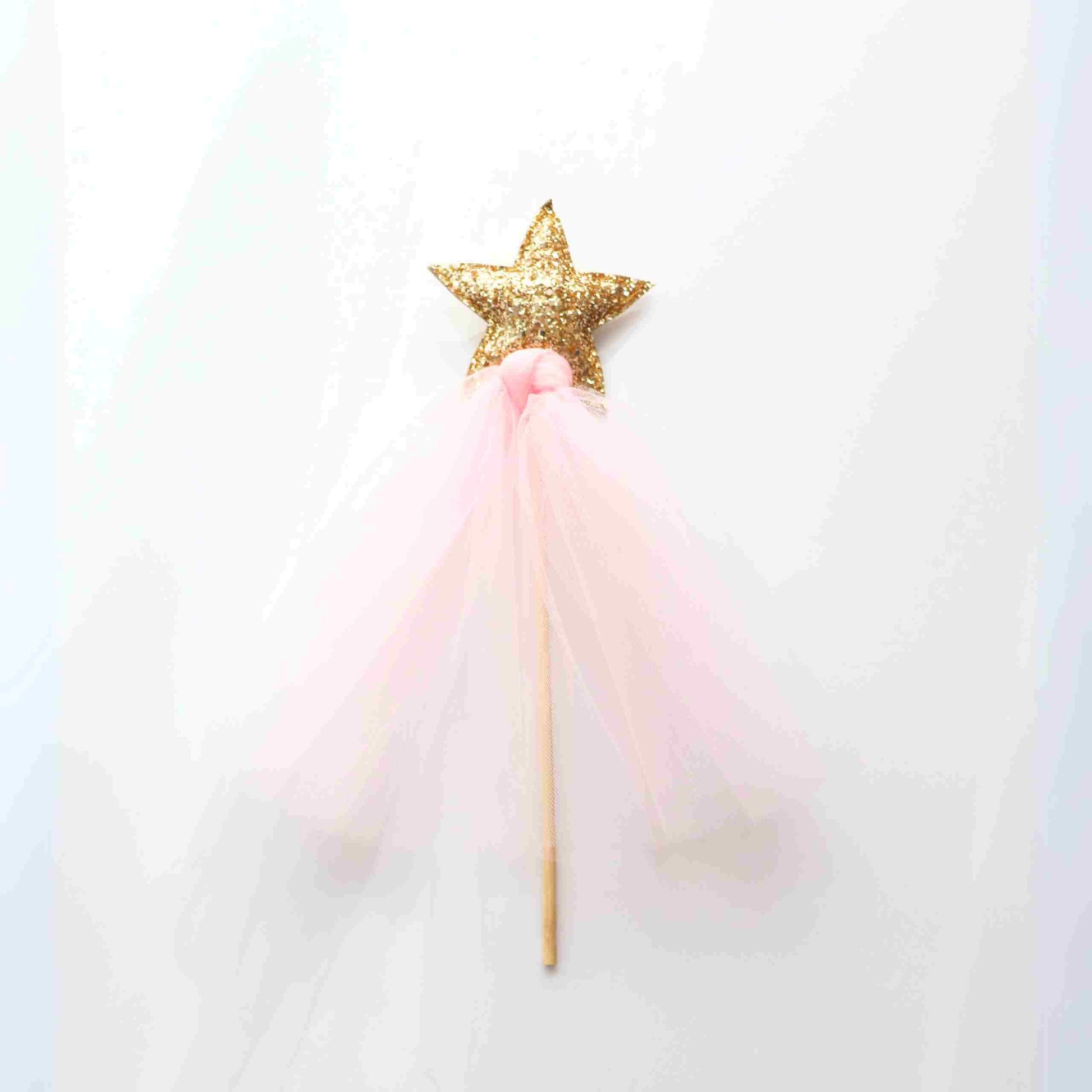 a pink and gold star wand on a white background