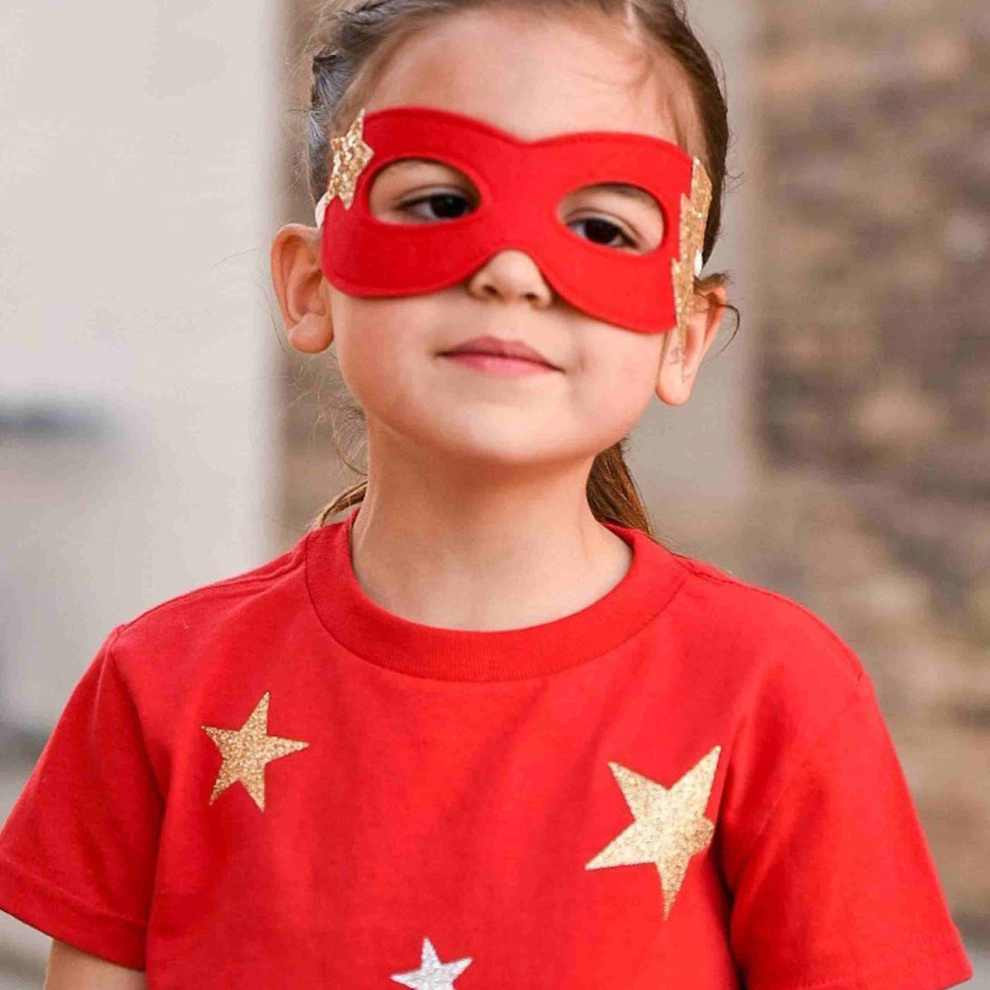 a little girl wearing a red mask and stars on her face