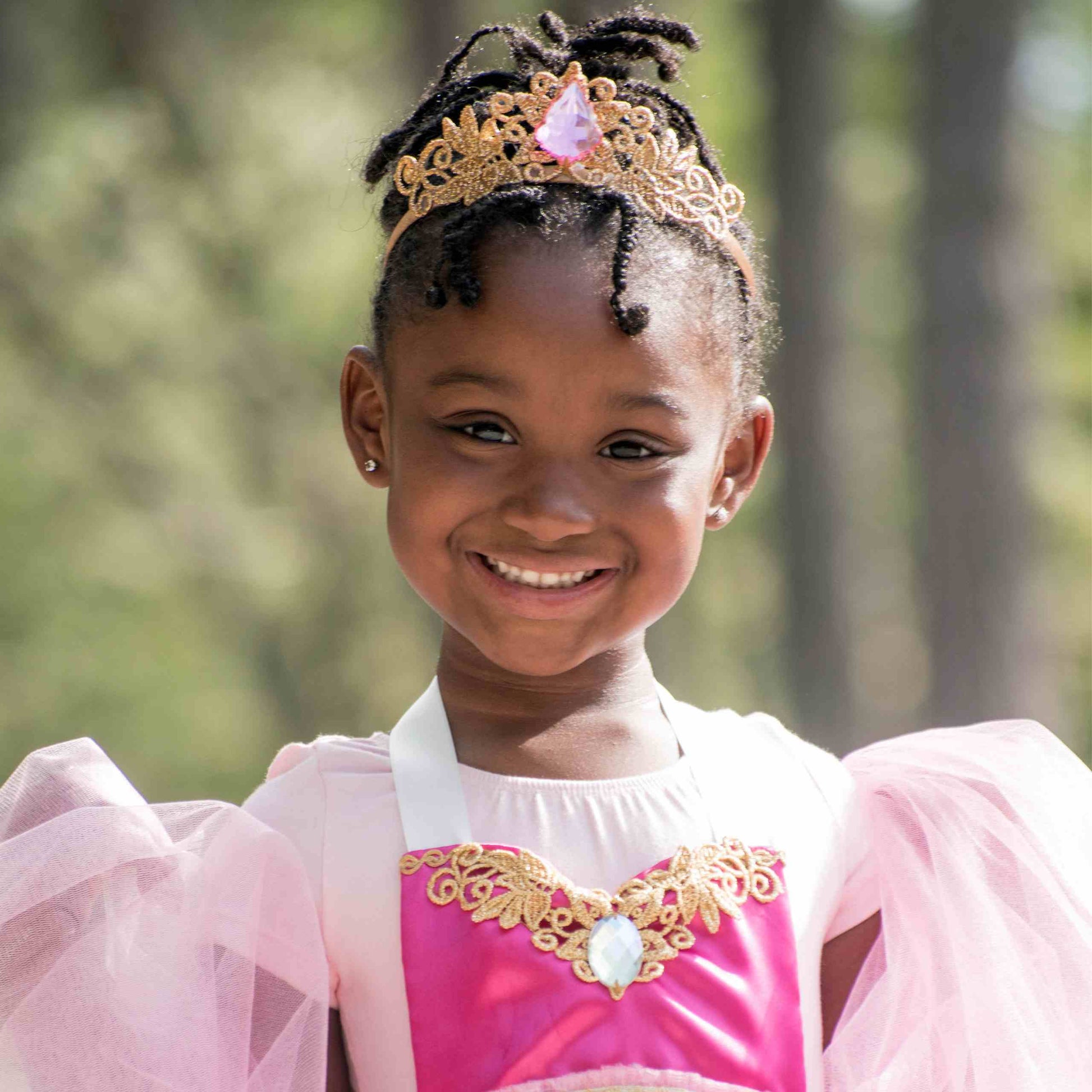 a little girl wearing a pink and gold dress