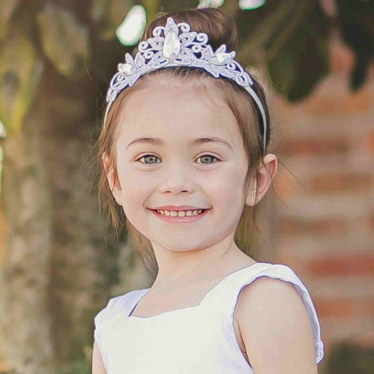 a little girl wearing a tiara smiling for the camera