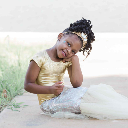 a little girl sitting on the ground with a dress on