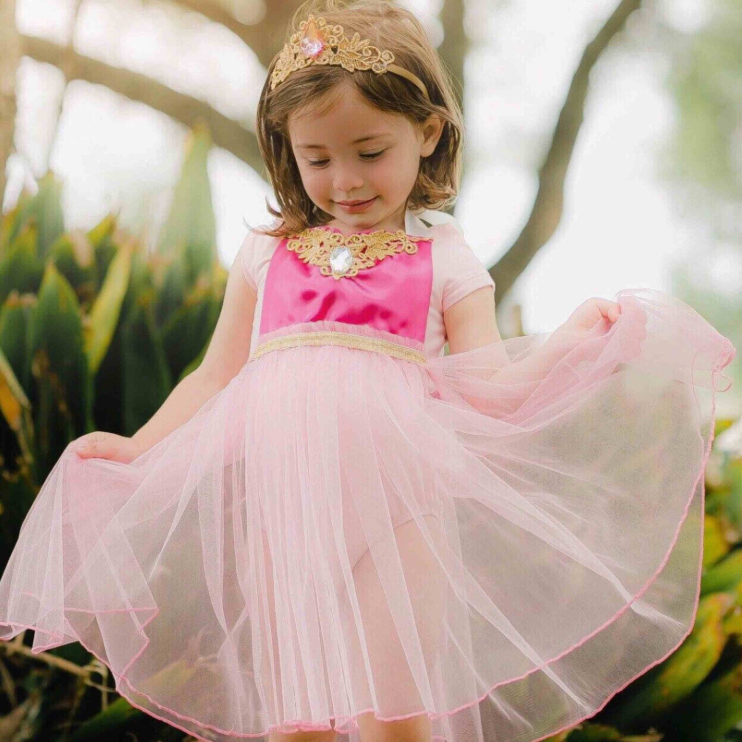 a little girl wearing a pink dress and a tiara