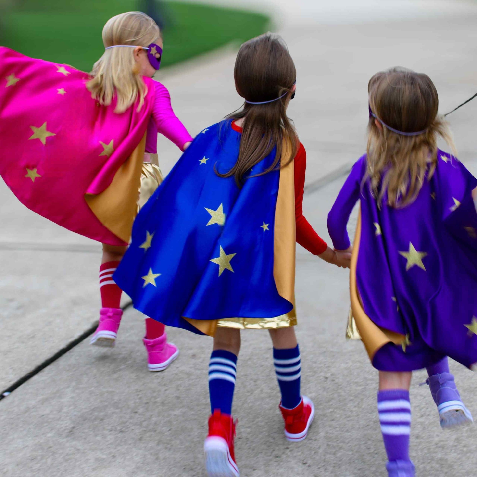 three little girls walking down a sidewalk holding hands