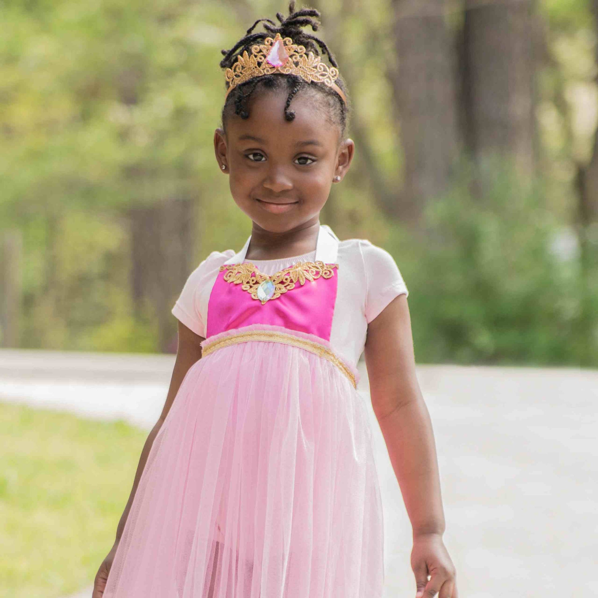 a little girl wearing a pink dress and a tiara