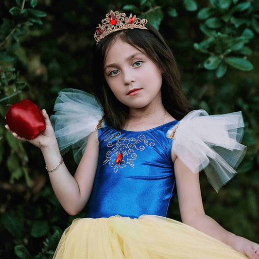 a little girl dressed in a princess costume holding an apple