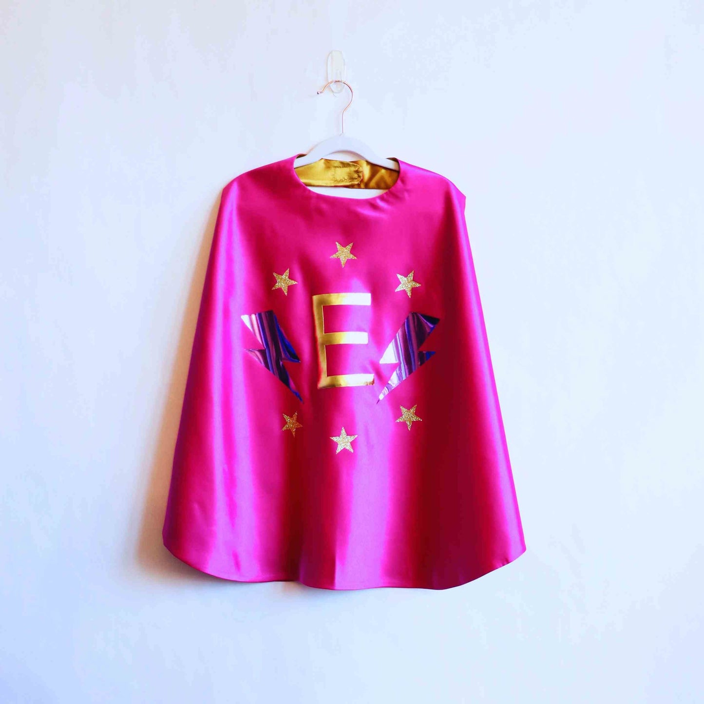 a pink cape hanging on a white wall