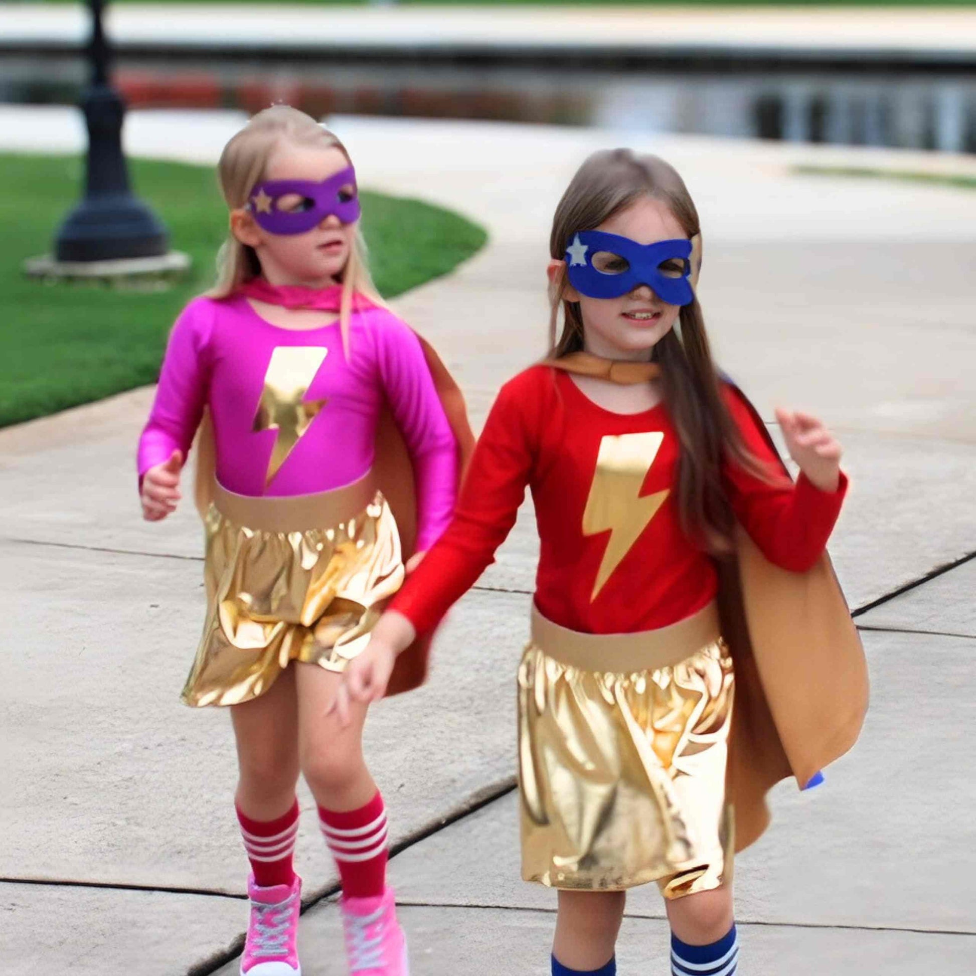 two little girls dressed in costumes walking down a sidewalk