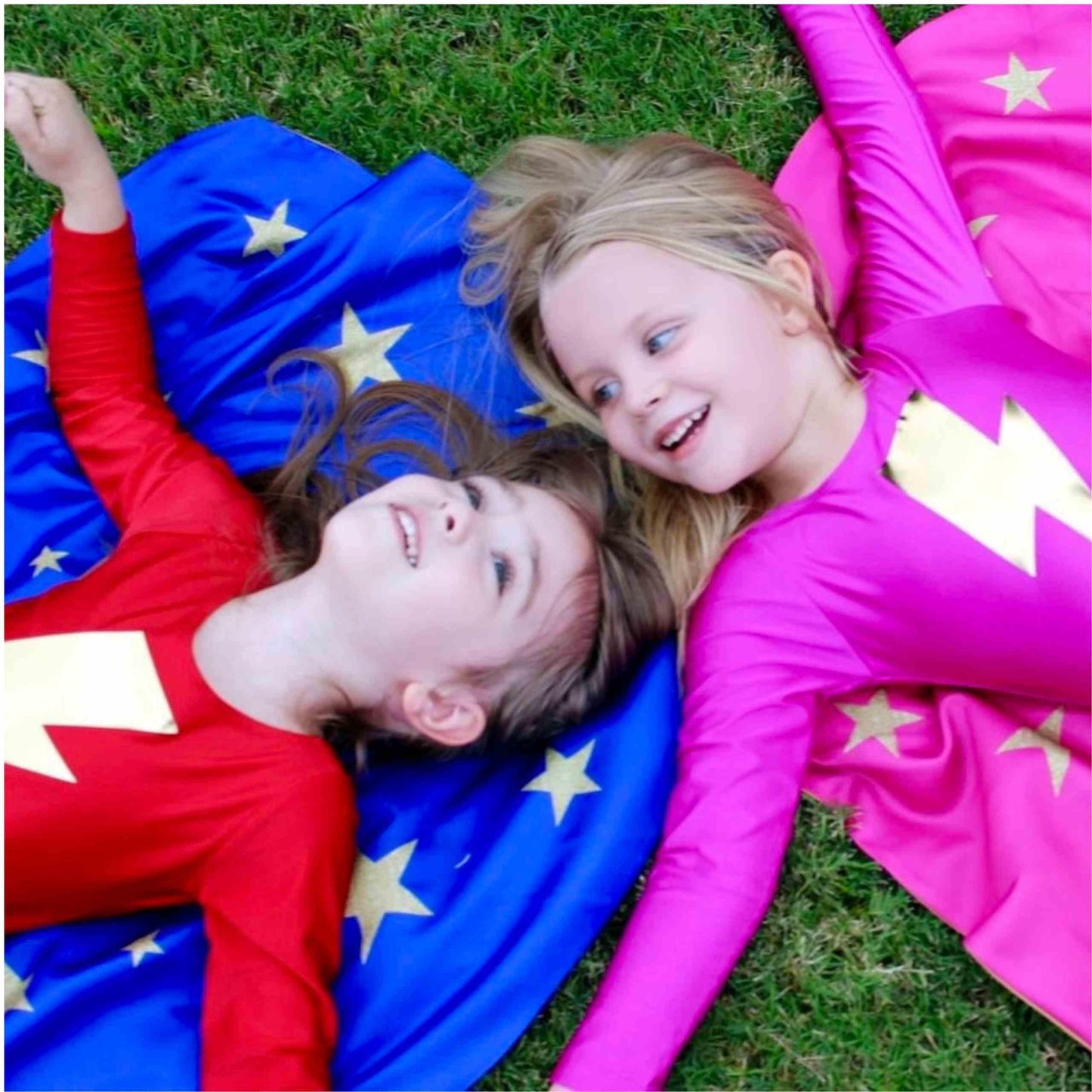two girls laying on a blanket in the grass