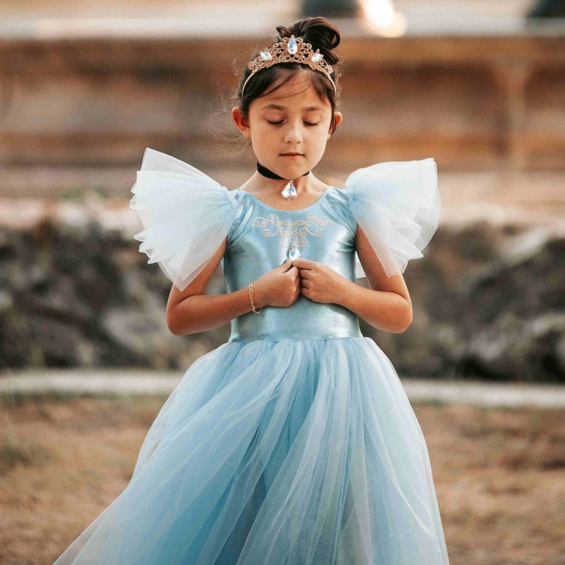 a little girl wearing a blue dress and a tiara